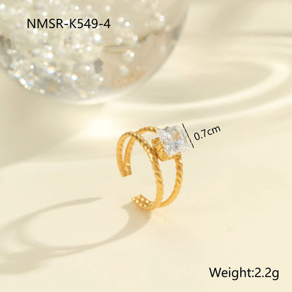 Gold electroplated stainless steel open mouth ring with geometric shapes and zircon inlay on a heart drop.
