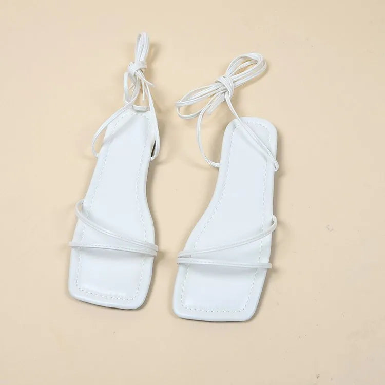 Women's black flat sandals with bandage ankle wrap and front lace-up fastening on a white background.