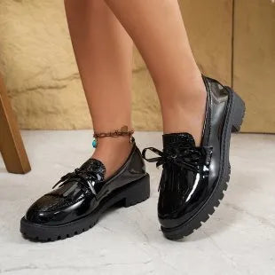 Women's black slip-on loafer shoe with a decorative bow on the front.