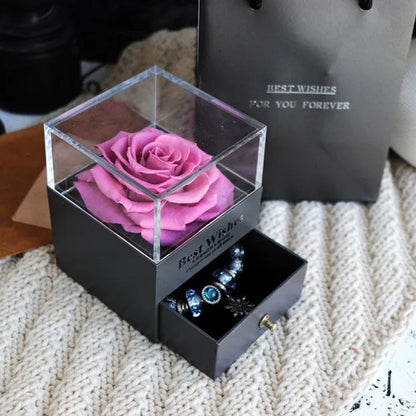 Blue and pink eternal flower gift box with roses and carnations on a table.