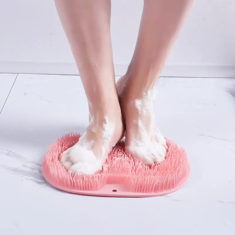 Orange non-slip massage bath brush with silicone bristles and suction cup base on shower floor