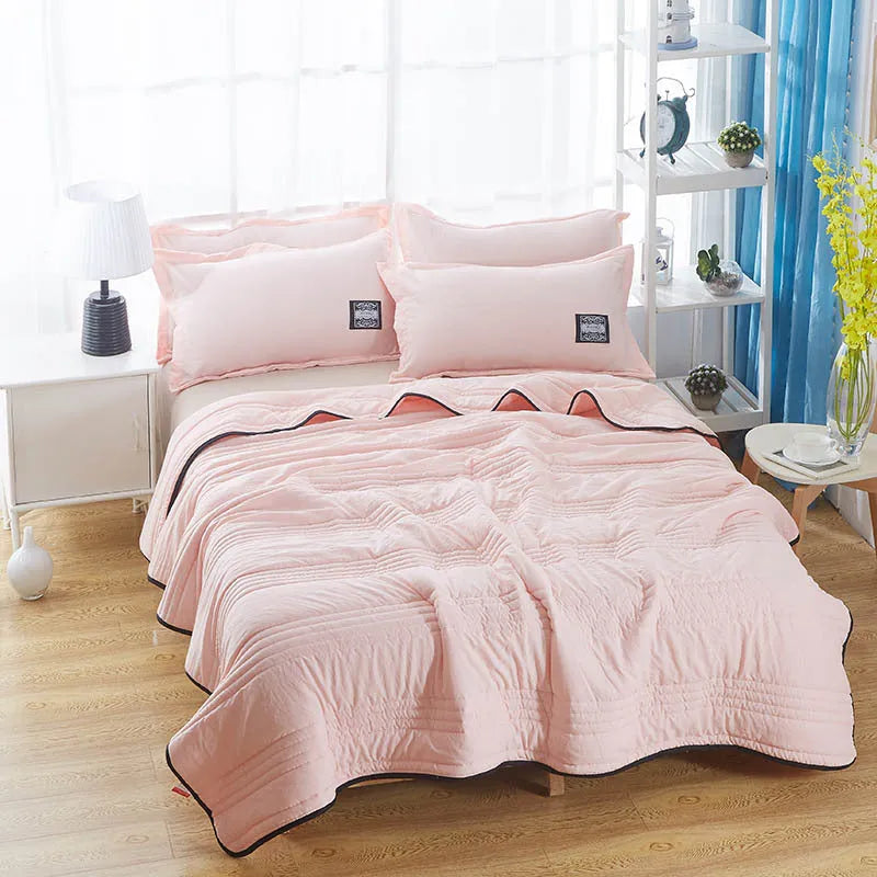 Lightweight plain coloured polyester summer quilt on a bed