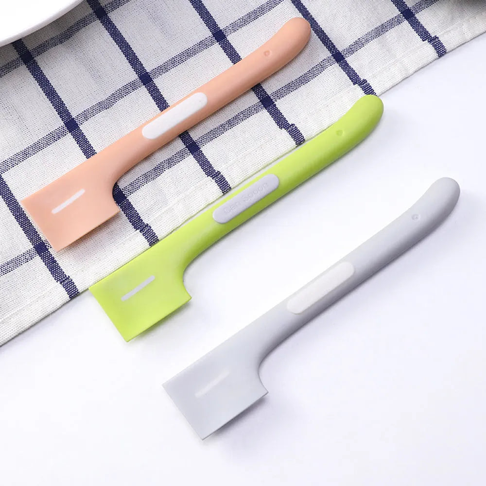 Green long-handled plastic spoon for scooping pet food from a can.