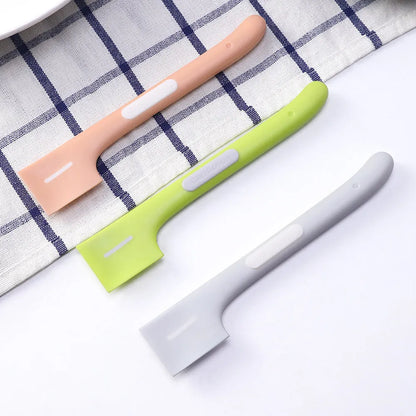 Green long-handled plastic spoon for scooping pet food from a can.