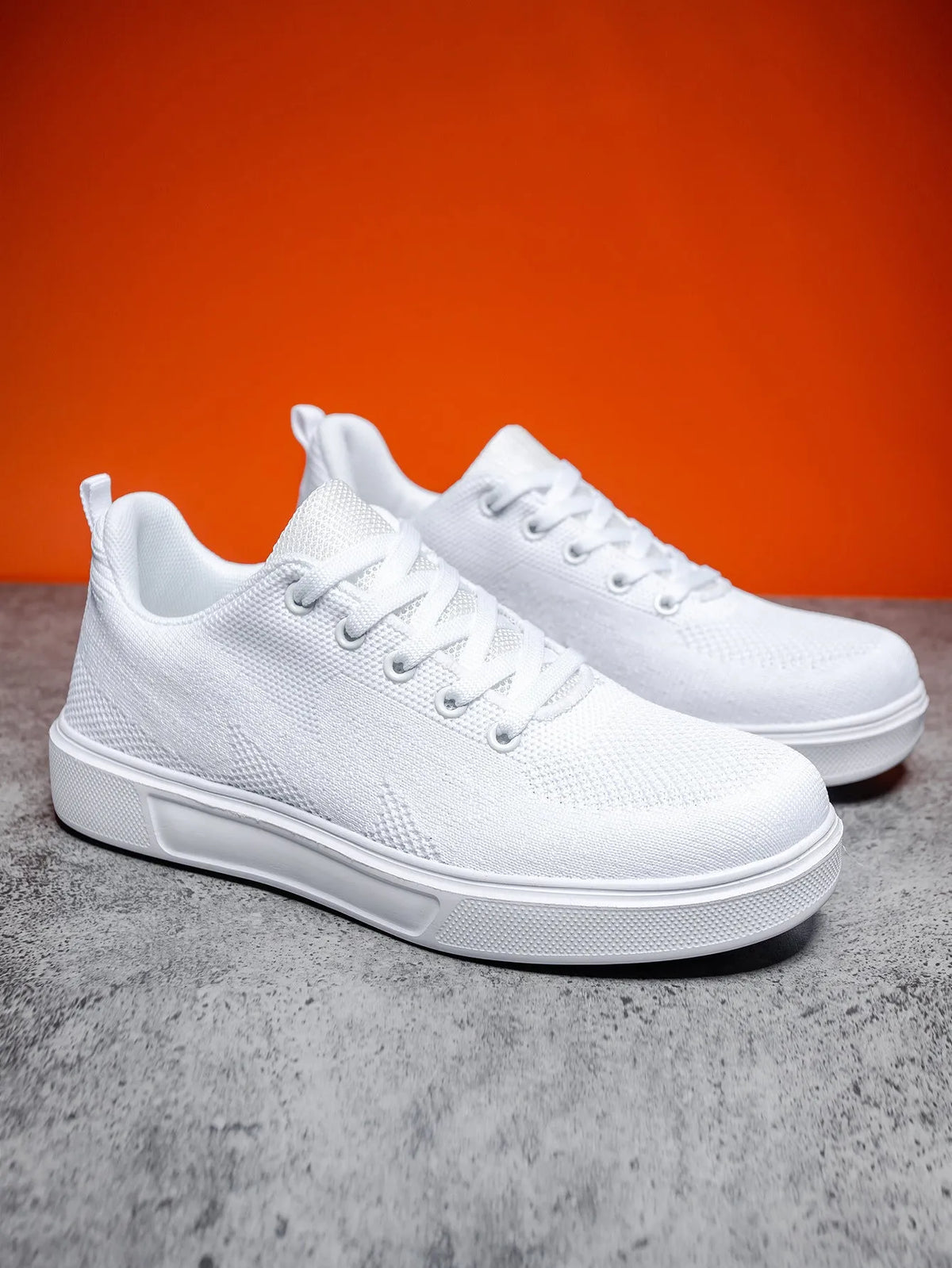 Pair of light white thick-soled casual sneakers with mesh upper and lace-up front.