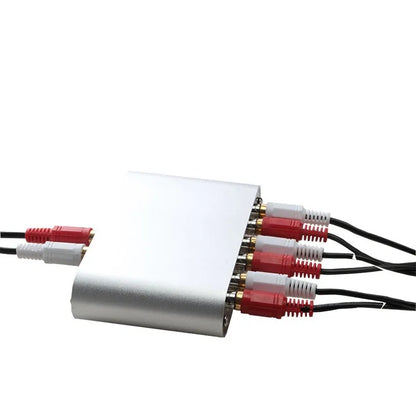 Silver aluminium audio source switch selector unit with infrared remote control on a black surface.