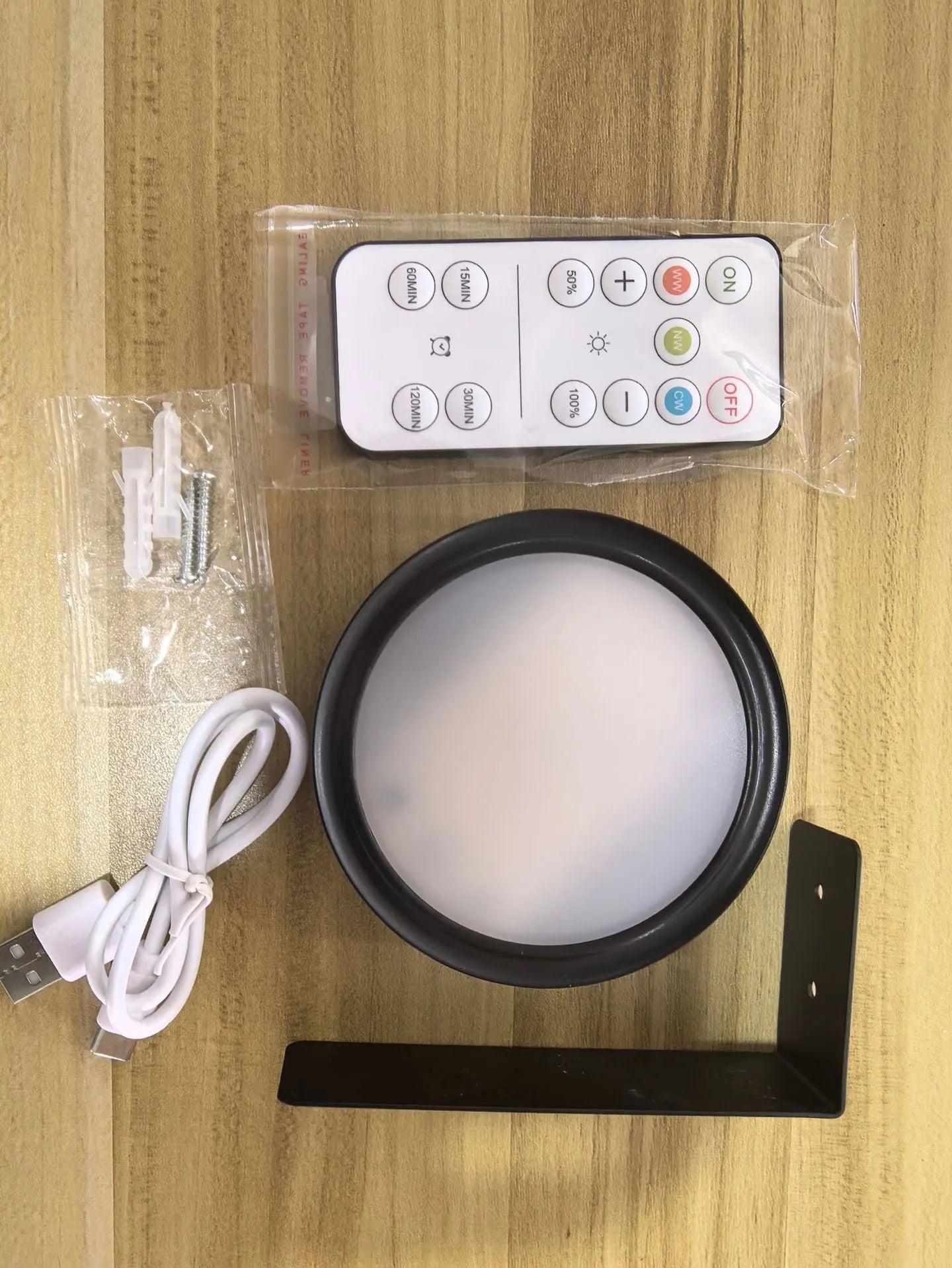 Black magnetic LED painting lamp with remote control on a white wall.