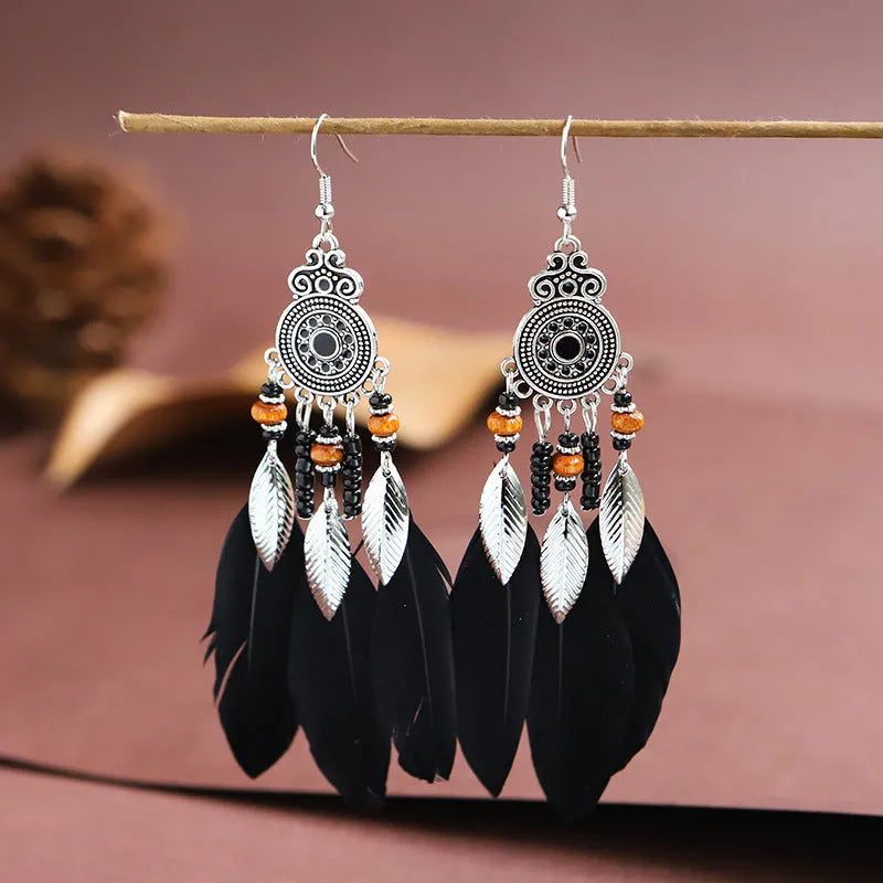 Bohemian feather leaf pattern alloy earrings in round drop shape on a colour selection background.
