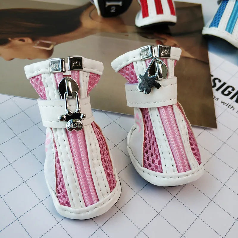 Four blue cloth dog shoes with zippers and non-slip soles laid out for a small dog.