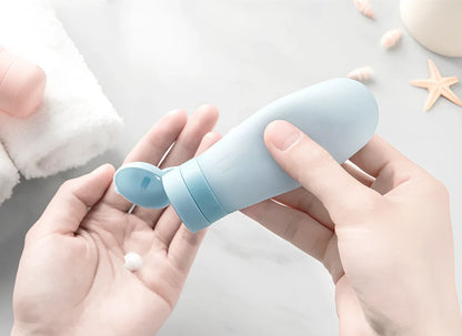 Set of three silicone travel bottles in light grey, pink, and blue colours with screw caps