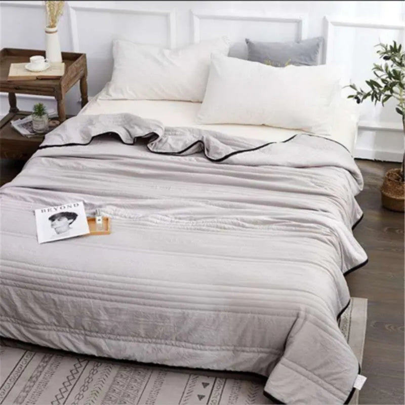Lightweight plain coloured polyester summer quilt on a bed