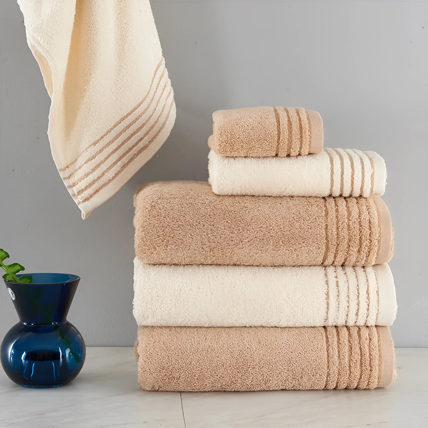Beige and brown cotton towel set showing bath, hand, and face towel sizes.