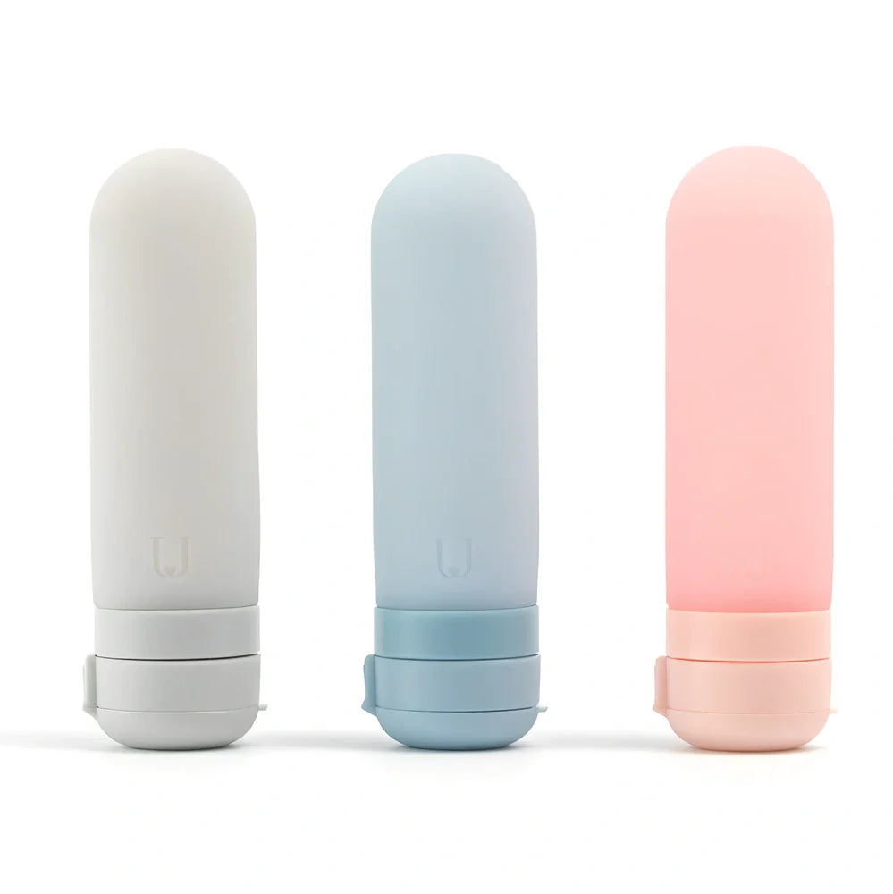 Set of three silicone travel bottles in light grey, pink, and blue colours with screw caps