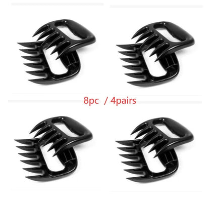 Two black bear claw meat shredders with decorative handles on a kitchen surface.