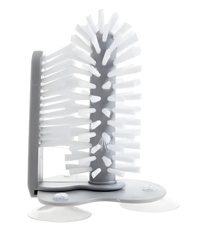 Grey rotating double-head cup brush with suction cups for wall mounting.