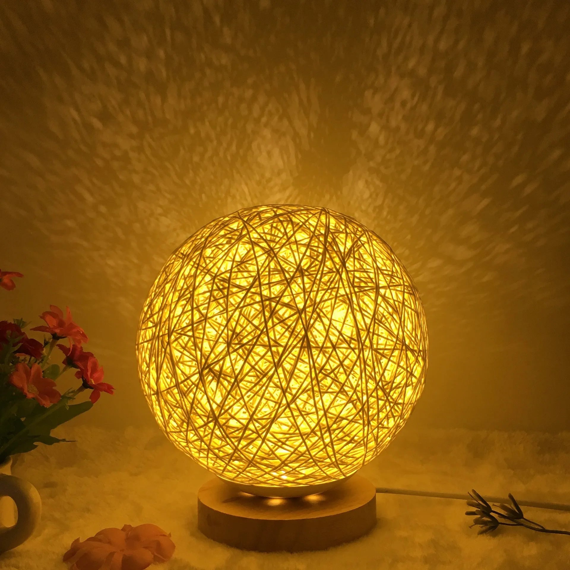 Spherical hand-knitted rattan table lamp with remote control on a wooden desk