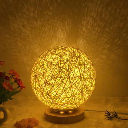 Spherical hand-knitted rattan table lamp with remote control on a wooden desk