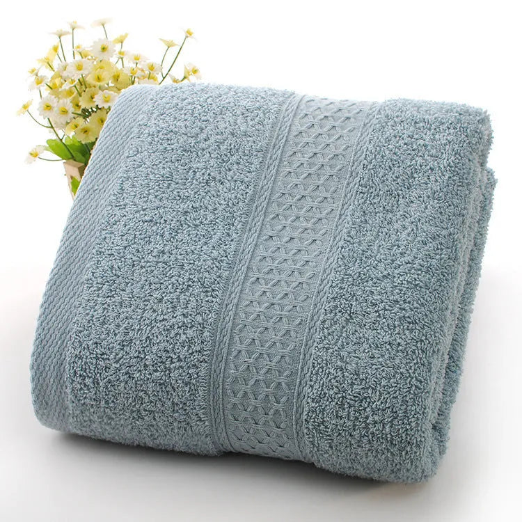 A stack of thickened cotton bath and beach towels in various colours including apple green, dark blue, and light pink.