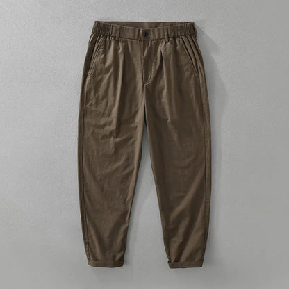 Man wearing loose beige straight-leg cotton linen trousers in a casual setting
