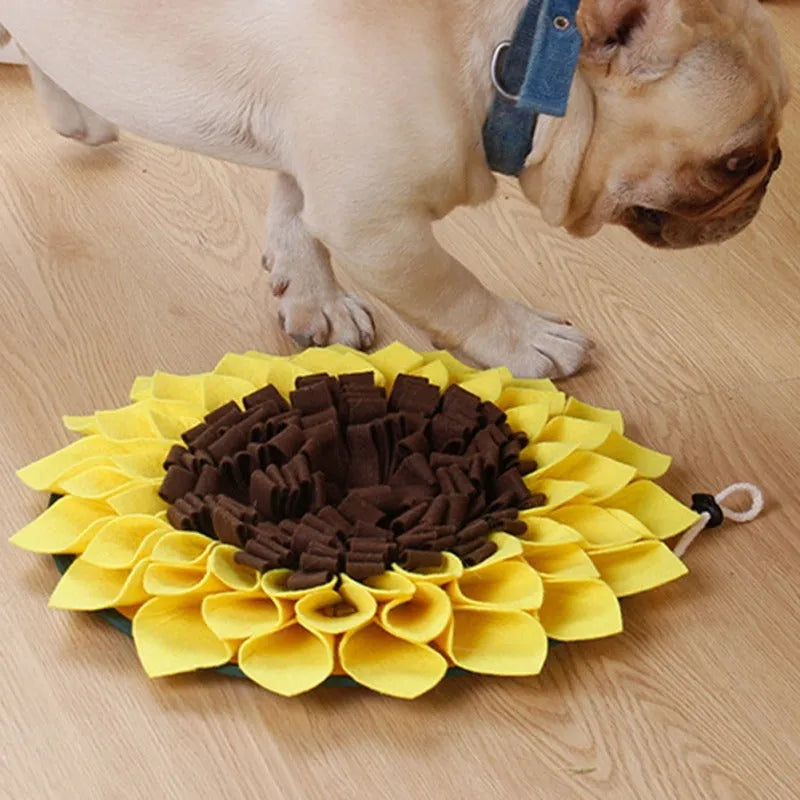 Yellow sunflower-shaped dog snuffle mat for slow feeding and nosework training on a floor.