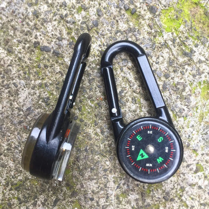 Black outdoor carabiner with a built-in circular compass and thermometer display on its side.