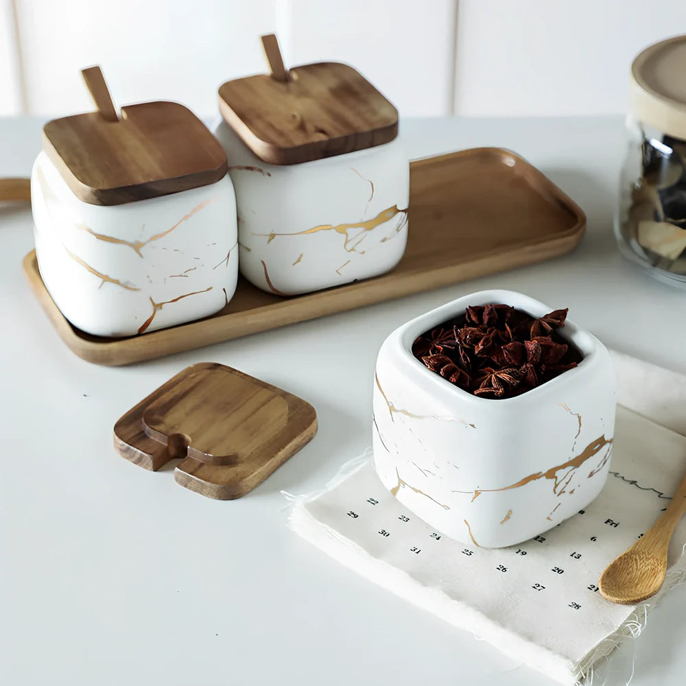 Three-piece Nordic Gold Marble Jar Set in white ceramic with wooden tray and bamboo spoons on kitchen counter