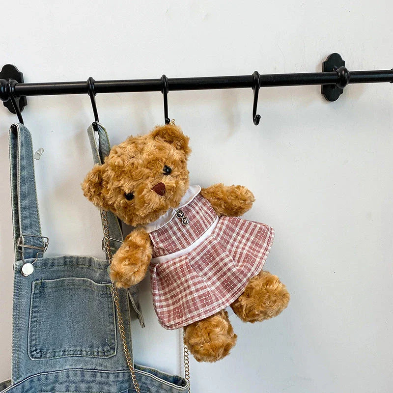 A plush teddy bear crossbody messenger bag with an adjustable shoulder strap and a zippered interior pocket for convenient storage.
