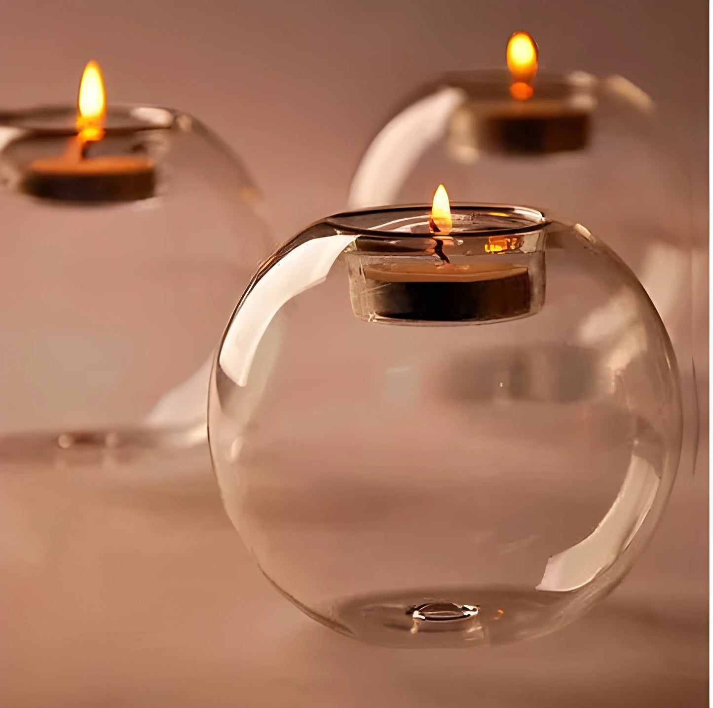 Handmade round hollow glass candle holder in three sizes on a table.