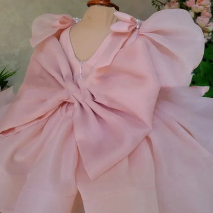 Pink flower girl dress with puffy sleeves and princess bow, shown on mannequin