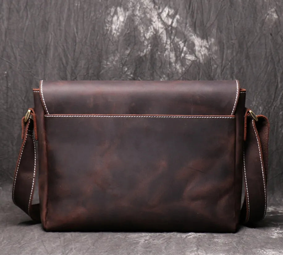 Vintage brown leather men's messenger bag with a cover flap, showing the internal document and phone pockets.