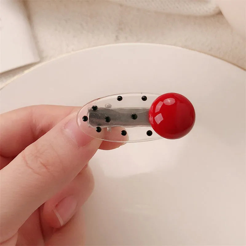 Red plastic hair clip with a 3D love heart and dots on a willow leaf-shaped base.