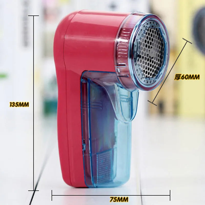 White portable electric lint remover on a blue sweater, showing compact size and shaver head.