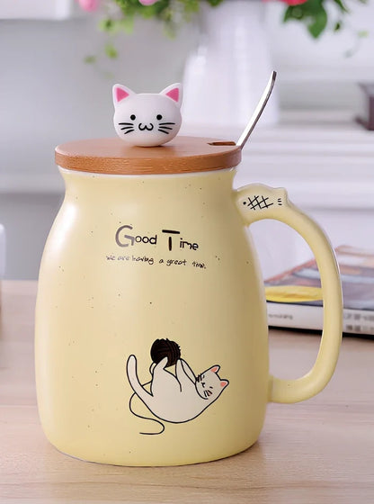 Pink ceramic mug with cartoon cat design, wooden lid, and stainless steel spoon on table