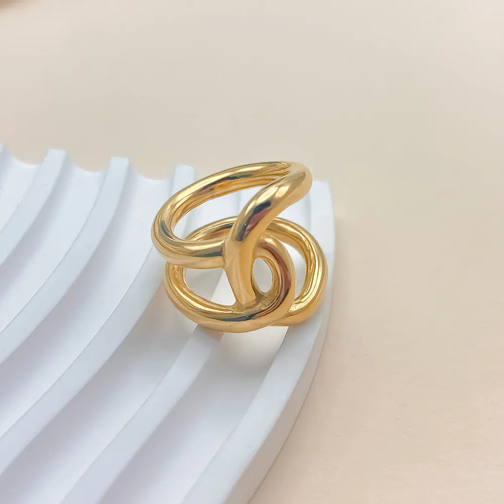 Knotted adjustable stainless steel ring for women in gold or steel colour on a grey background.