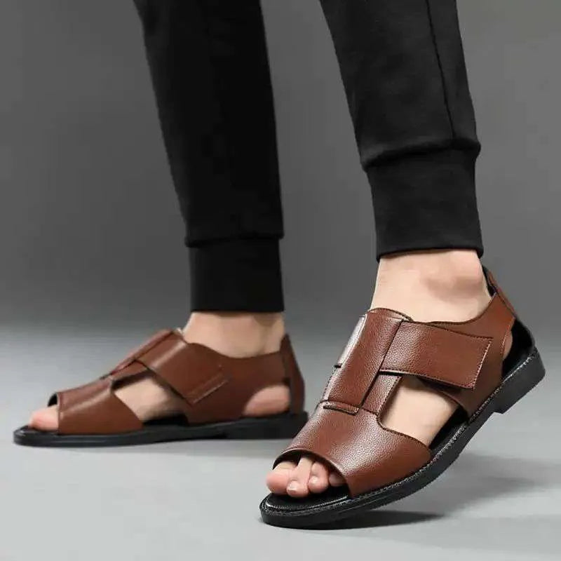 Men's brown leather Roman-style sandals with an open toe and a textured rubber sole on a wooden surface.