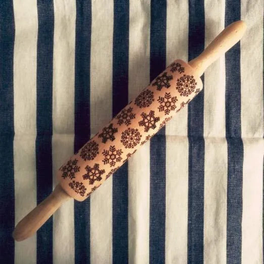 Wooden rolling pin with engraved Christmas patterns including reindeer and snowflakes on a 45cm long barrel.