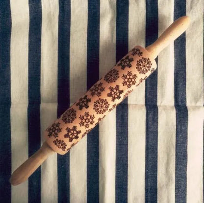Wooden rolling pin with engraved Christmas patterns including reindeer and snowflakes on a 45cm long barrel.