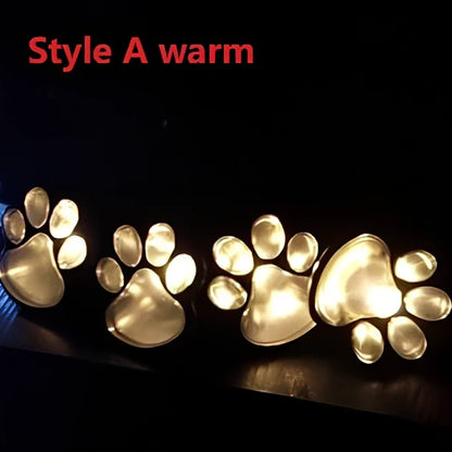 Four black paw-shaped solar garden lights with connecting wire and central solar panel for automatic outdoor illumination