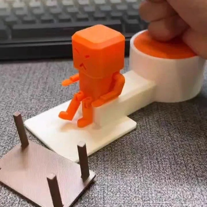 Orange plastic vent decompression toy with turning table mechanism on a desk.