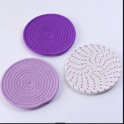 Set of three round grey cotton cord coasters, each 18cm in diameter, on a wooden table.