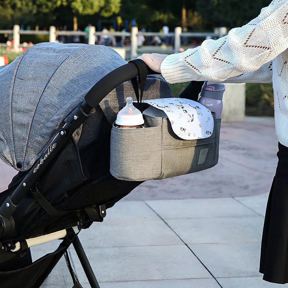 Baby stroller organiser with cup holder mounted on pram pole showing storage compartments