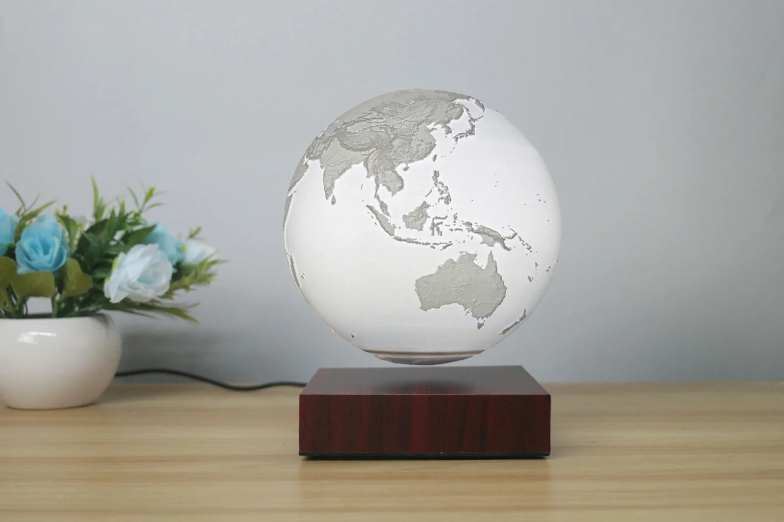 Levitating Earth or Jupiter lamp floating above base with LED illumination