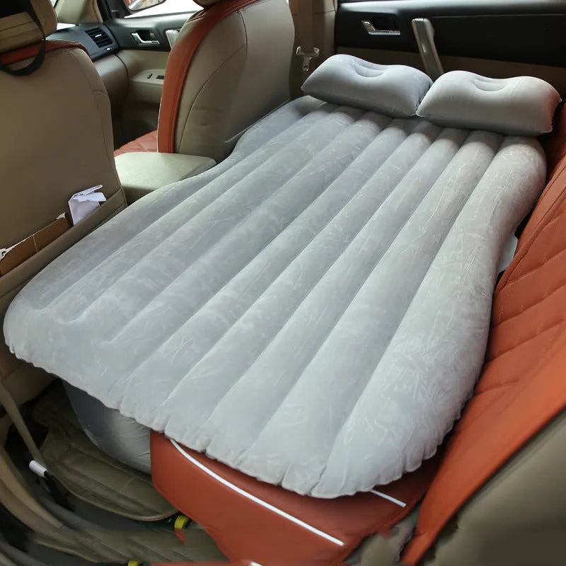Black inflatable car bed with flocked surface and two pillows, shown folded into a chair inside a vehicle.