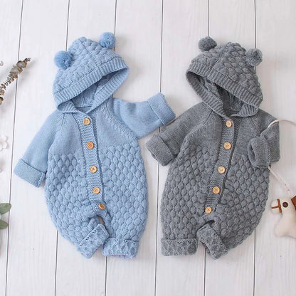 Baby wearing light blue knitted romper with hood and sleeveless design, single-breasted closure visible
