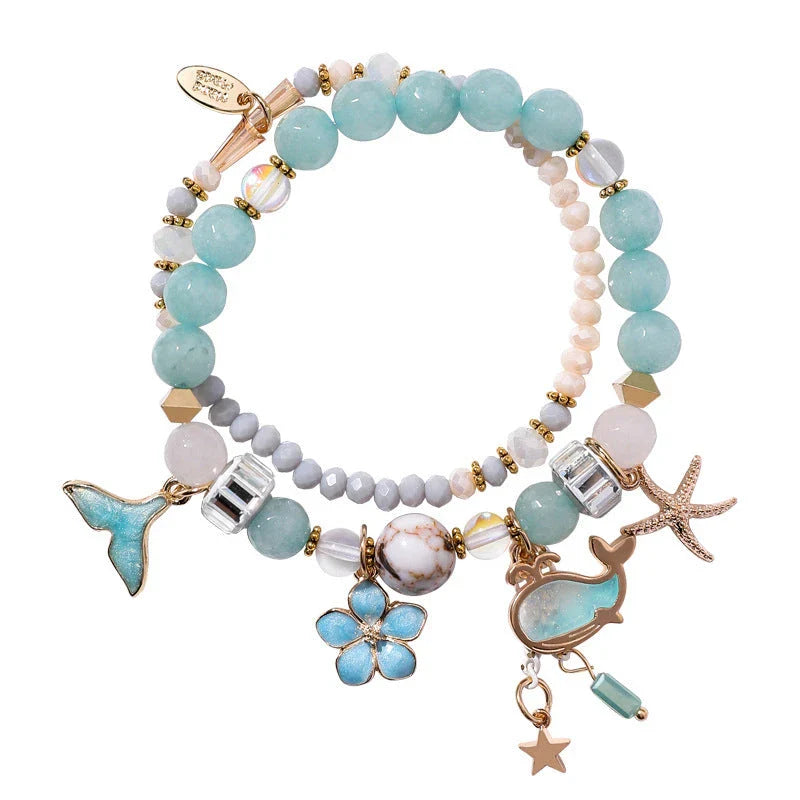 Elegant whale tail bracelet in vibrant colors with flower and starfish accents, perfect for adding a touch of coastal charm to any outfit.
