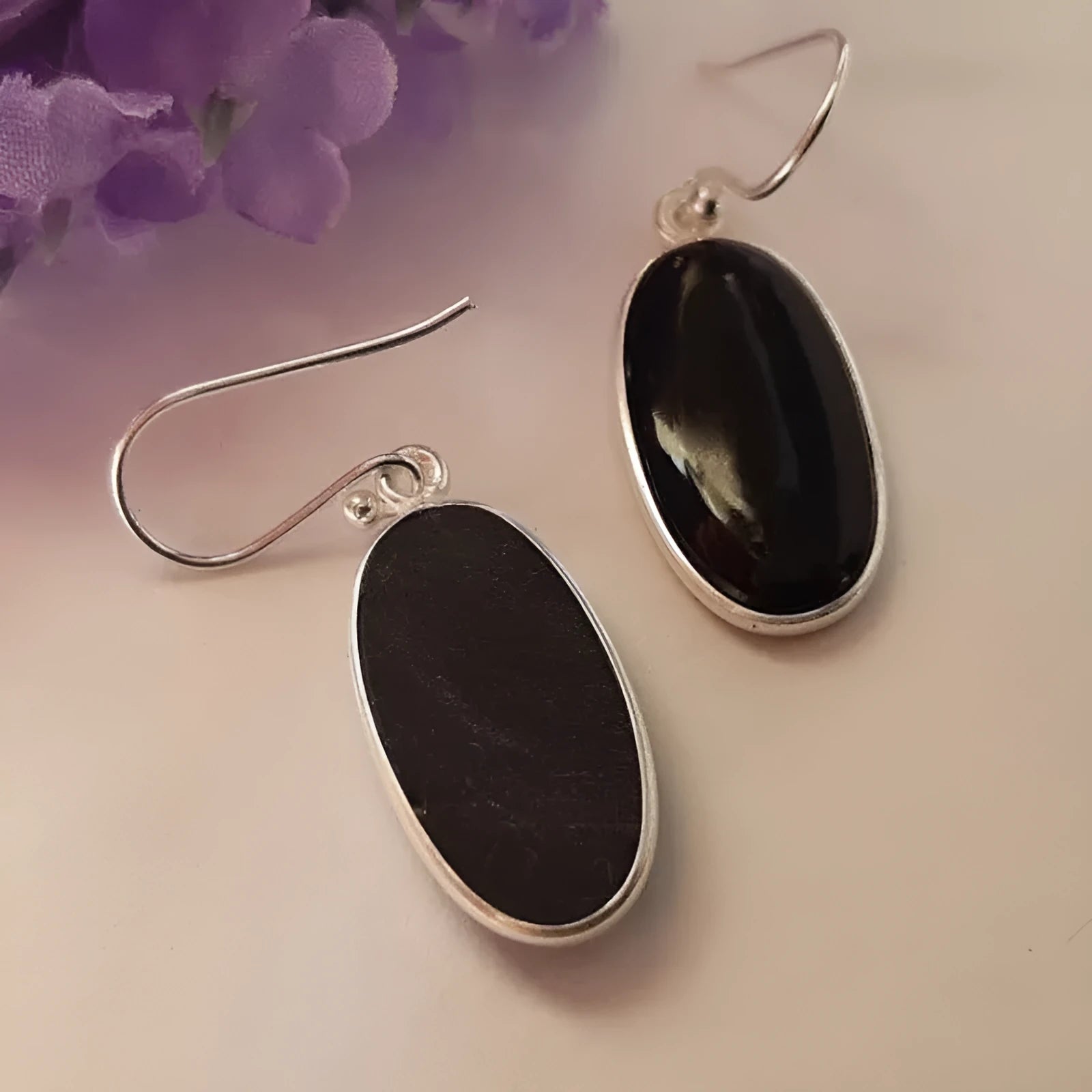 Women's geometric earrings with a black oval agate pendant in a silver electroplated frame.