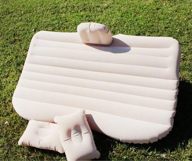Black inflatable car bed with flocked surface and two pillows, shown folded into a chair inside a vehicle.