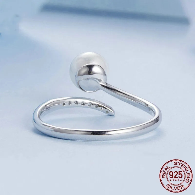 Silver adjustable open ring with white shell pearls on a white background.