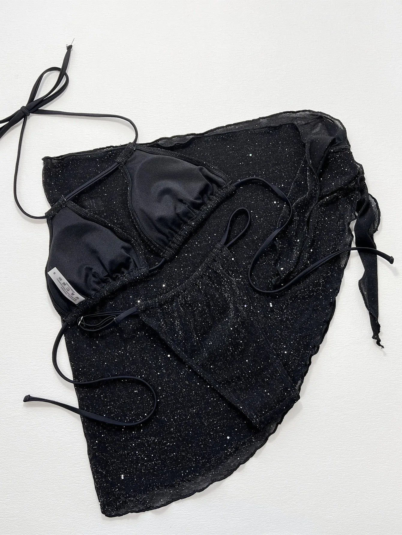 Black three-piece swimsuit bikini set with a top and shorts laid flat.