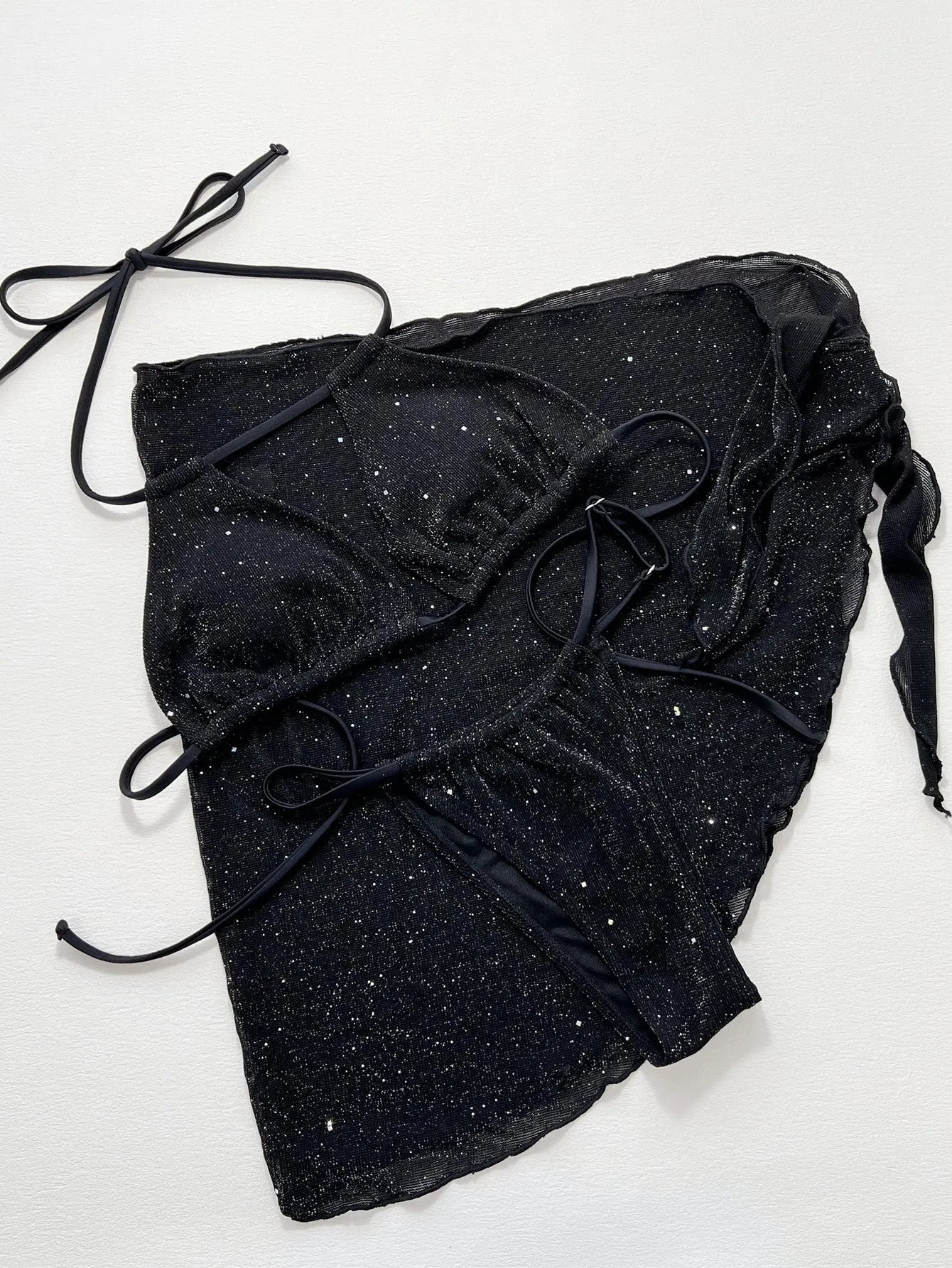 Black three-piece swimsuit bikini set with a top and shorts laid flat.